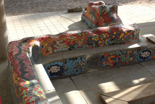 ein langer farbenfroher Lindwurm schlängelt sich um die Sandkiste- mit Schülermosaiken